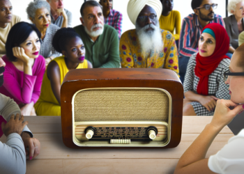 An image showing a crowd gathered around a radio listening to a broadcast, indicating mass communication.
