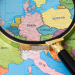 A magnifying glass placed on a world map, symbolic of detective work across European territories