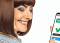 A woman smiling at her mobile phone, indicating the successful use of a cashback app