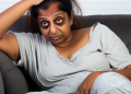 An exhausted person sitting on a couch emphasizing physical fatigue due to stress