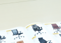 A detailed guidebook on various office chair models displayed on an office desk