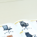 A detailed guidebook on various office chair models displayed on an office desk